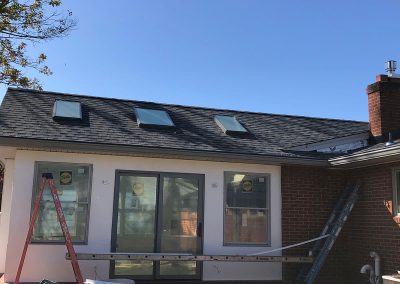 Several ladders in front of a brick building with light gray gutters