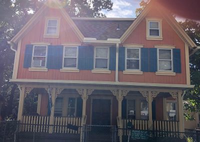 An orange house with a porch and white gutters