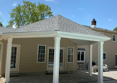 A gray shingled patio with white columns and white gutters