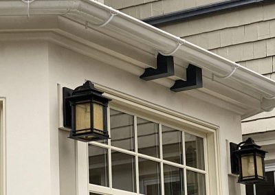 White gutters over a window and black metal lamps