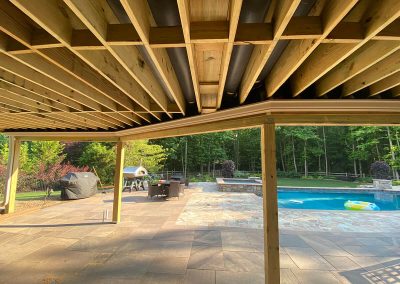 White gutters running underneath the wooden beams of a porch ceiling