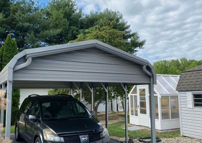 A car under a small gray roof with gray gutters