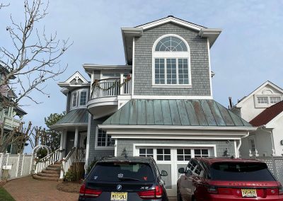 An old two-story house with white gutters and two cars in the driveway