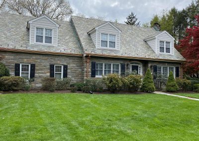 A gray stone house with a stone roof and copper gutters