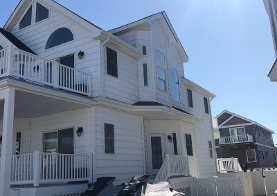 A two-story white house with a balcony and white gutters