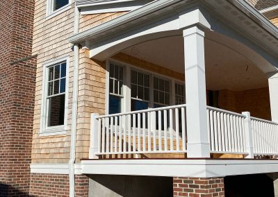 A yellow brick building with white gutters and a white porch