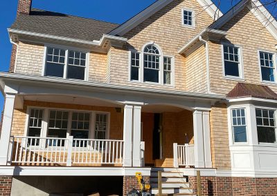 A two-story yellow brick house with white gutters