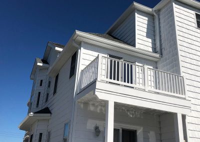 A white building with a white balcony and white gutters