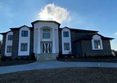 A large brownstone house with dark gutters and a concrete porch