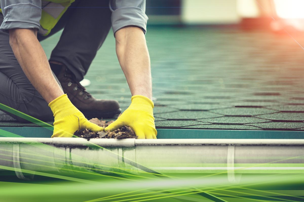 male contractor cleaning leaves from gutter