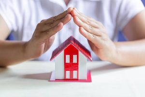 person shielding house model with hands gutter damage van's rain gutters